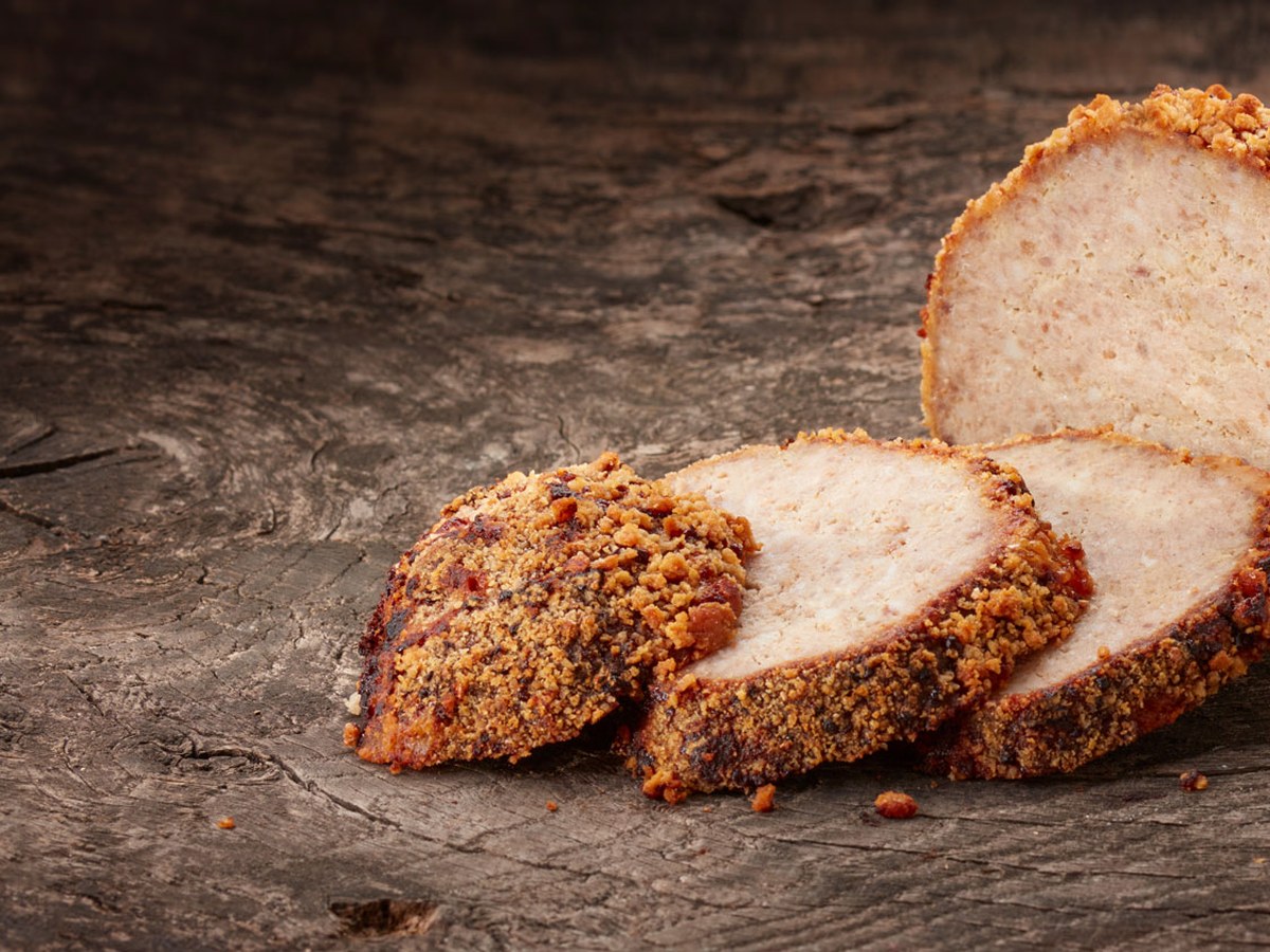 Gehaktbrood met krokante korst, aangesneden op een houten plank